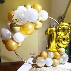 the balloon arch is decorated with gold, white and silver balloons that spell out the number thirteen