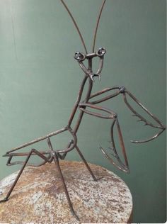 a metal insect sculpture sitting on top of a rock