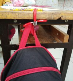 the back end of a backpack hanging on a school desk with a child's toy in the background