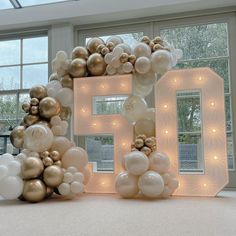 the number five is made out of balloons and lights in front of a large window