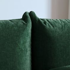 a close up view of the back of a green couch with two pillows on it