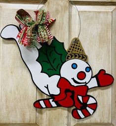 a door hanger with a christmas decoration hanging from it's side, and an image of a snowman holding a holly berry