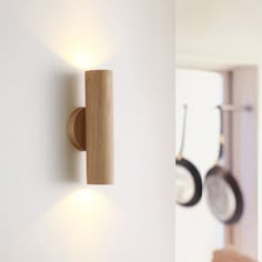 a wall mounted light on the side of a white wall next to pots and pans