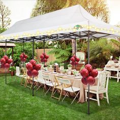 an outdoor dining area with tables and chairs covered in white tents, balloons and lights