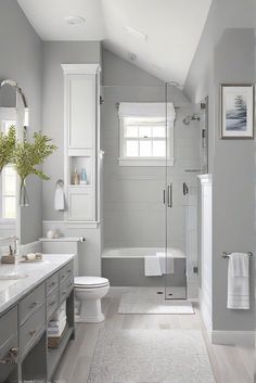 a white bathroom with gray walls and wood flooring, along with a walk in shower