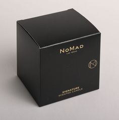 a black box with gold writing on the lid that says, nomad signature scented candle