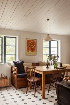 a dining room table and chairs in front of two windows with wood trimmings