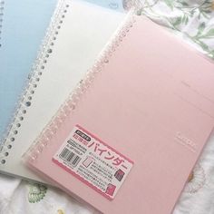 three notebooks sitting on top of a bed next to each other