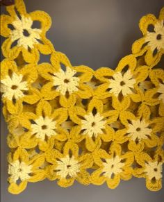 a crocheted yellow and white doily with flowers on it's side