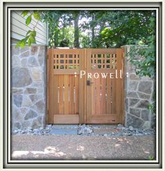 two wooden doors are open in front of a stone wall and trees with leaves on it