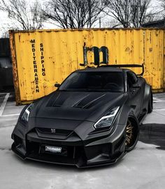 a black sports car parked in front of a yellow shipping container