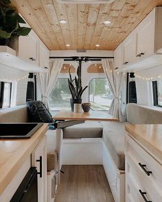 the interior of a camper with wood flooring and white walls, windows, and cabinets