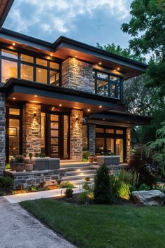 a modern house is lit up at night with lights on the front and side windows