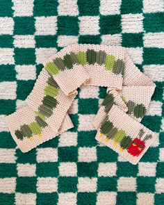 four knitted scarves sitting on top of a green and white checkered blanket