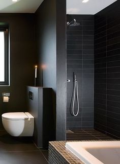 a black and white bathroom with a tub, toilet and shower head mounted to the wall