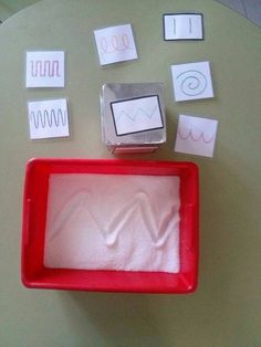 a red tray filled with pink powder next to cut outs and magnets on a table