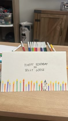 a birthday card with candles on it sitting on a table next to colored crayons