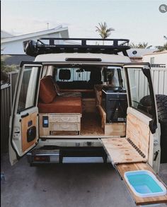 the back end of an old van with its door open and seats folded down in front