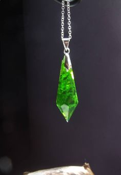 "Unique necklace in pendulum/crystal form. The pendant is filled with little glass pieces in a deep, glowing green. The pendant is 4cm tall and can be ordered with a black ribbon or silver necklace. The color of the little hanger can be chosen. This piece was handcrafted and is therefore unique.  Please note: Due to the crafting process the pieces in this form have a \"backside\". This means one of the facets can be mat, have a little edge or small bubbles. But of course all of my pieces are cra Green Crystal Pendant Jewelry, Green Round Pendant Crystal Necklace For Spiritual Use, Green Round Pendant Crystal Necklace For Spiritual Purposes, Spiritual Green Crystal Round Pendant Necklace, Spiritual Green Round Pendant Crystal Necklace, Green Spiritual Jewelry For Party, Green Spiritual Jewelry For Parties, Green Resin Round Pendant Necklace, Green Glass Pendant Jewelry