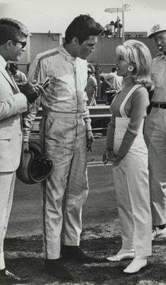 three men and two women standing in front of a firetruck talking to each other