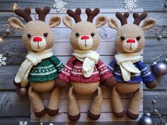 three crocheted reindeers wearing sweaters and scarves are hanging on a wall