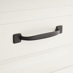 a black handle on a white cabinet door