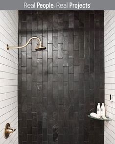 a black and white tiled bathroom with gold fixtures on the shower head, toiletries and soap dispensers