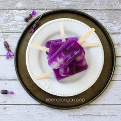 popsicles are on a white plate with purple flowers