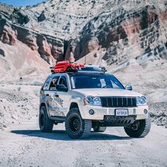 a white jeep parked in the desert with mountains in the background