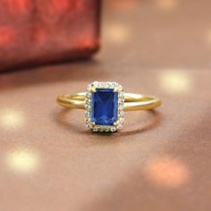 a gold ring with a blue stone surrounded by white and yellow diamonds on a table