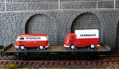 two red and white trucks are on the train tracks near a brick wall with arches