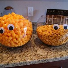 two glass bowls filled with candy corn and eyes on top of a granite countertop