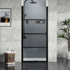 a bathroom with a shower, plant and pictures on the wall above it in black and white