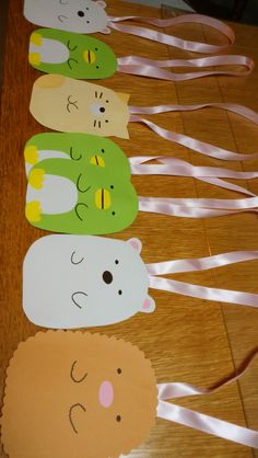 paper cut out animals lined up on a wooden table with white ribbon around the edges