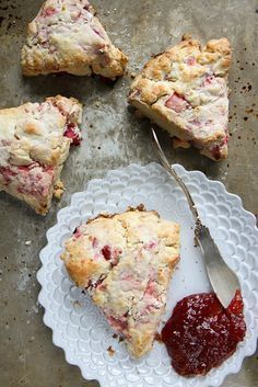 four pieces of strawberry scones on a plate with a fork and jam in the middle