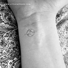 a small tattoo on the wrist of a woman's left arm, with an earth globe