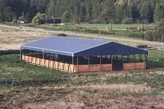 a large blue tent sitting on top of a lush green field next to a forest