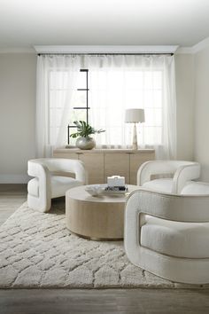 a living room with two white chairs and a coffee table in front of a window