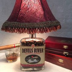 a lamp that is sitting next to a bottle and some cigars on a table