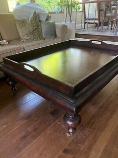 a large wooden table sitting on top of a hard wood floor next to a couch