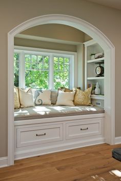 a window seat in the corner of a room with built - in bookshelves