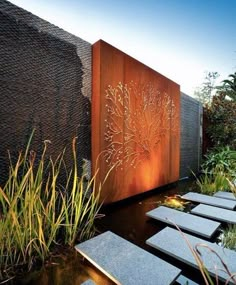 an outdoor area with benches, plants and water features in the background is a large metal screen