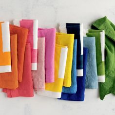 colorful towels are lined up on the wall next to each other, with one folded in different colors