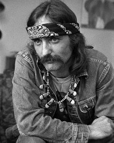 a man with long hair and a bandana on his head is sitting in front of a couch