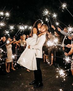 a newly married couple kissing while surrounded by sparklers