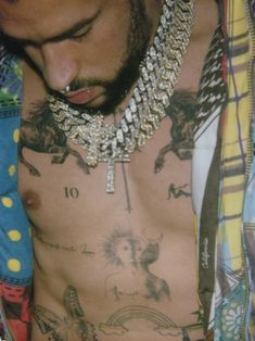 a shirtless man with multiple necklaces on his neck and chest is looking down