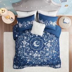 a bed with blue and white comforters on top of it next to a night sky