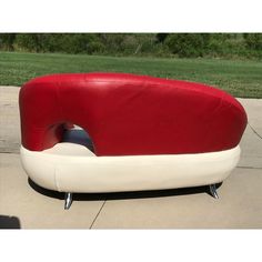 a red and white couch sitting on top of a sidewalk