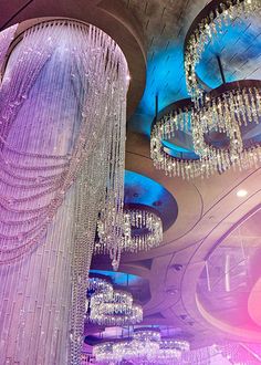 chandeliers hanging from the ceiling in a large room with blue and pink lighting