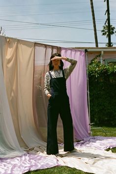 a woman standing in front of a pink and white curtain with her hands on her head